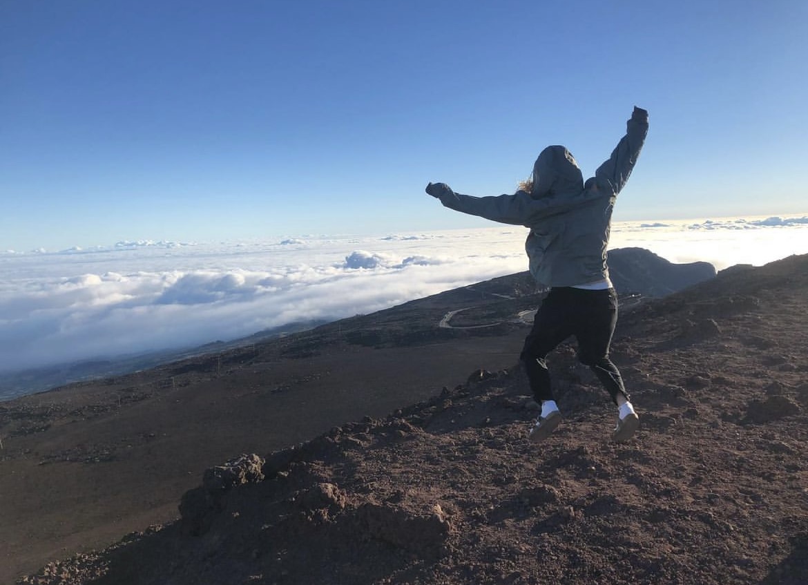 Girl jumping above the clouds of volcanic ground in Hawaii.