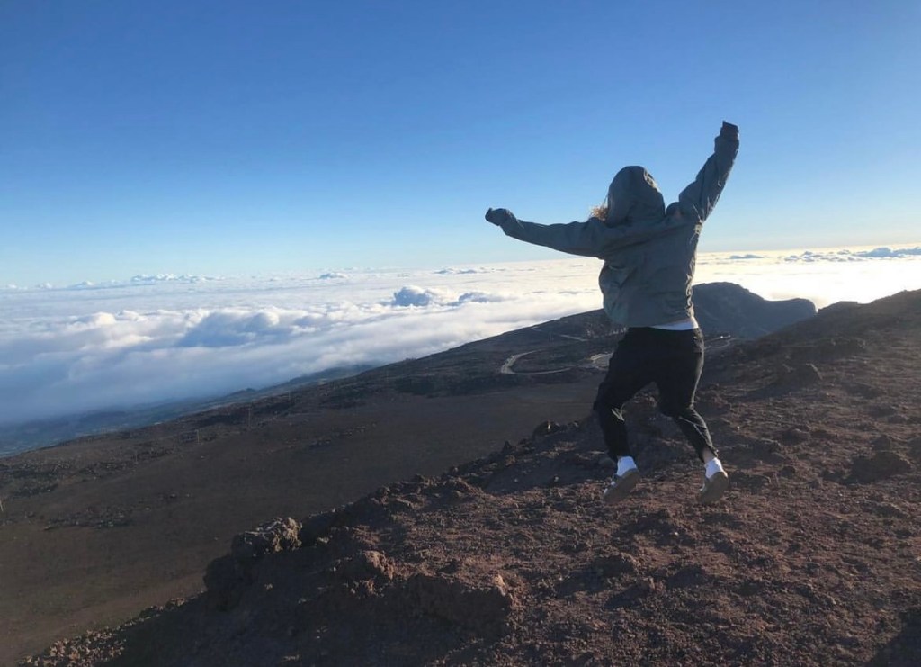 Girl jumping above the clouds of volcanic ground in Hawaii