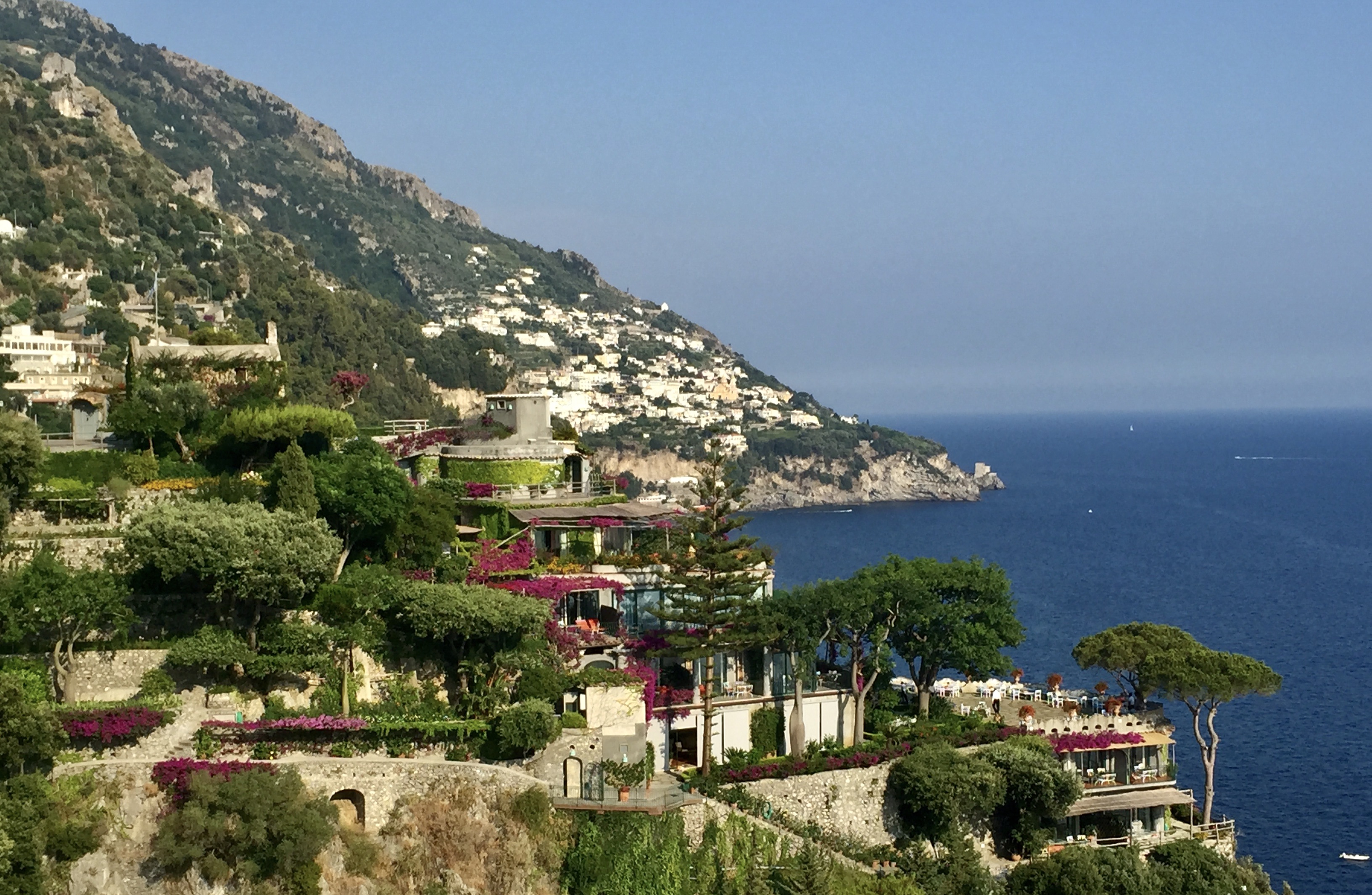 Coastal town of Italy overlooking the ocean. Lots of greenery, purple flowers, and light stone.