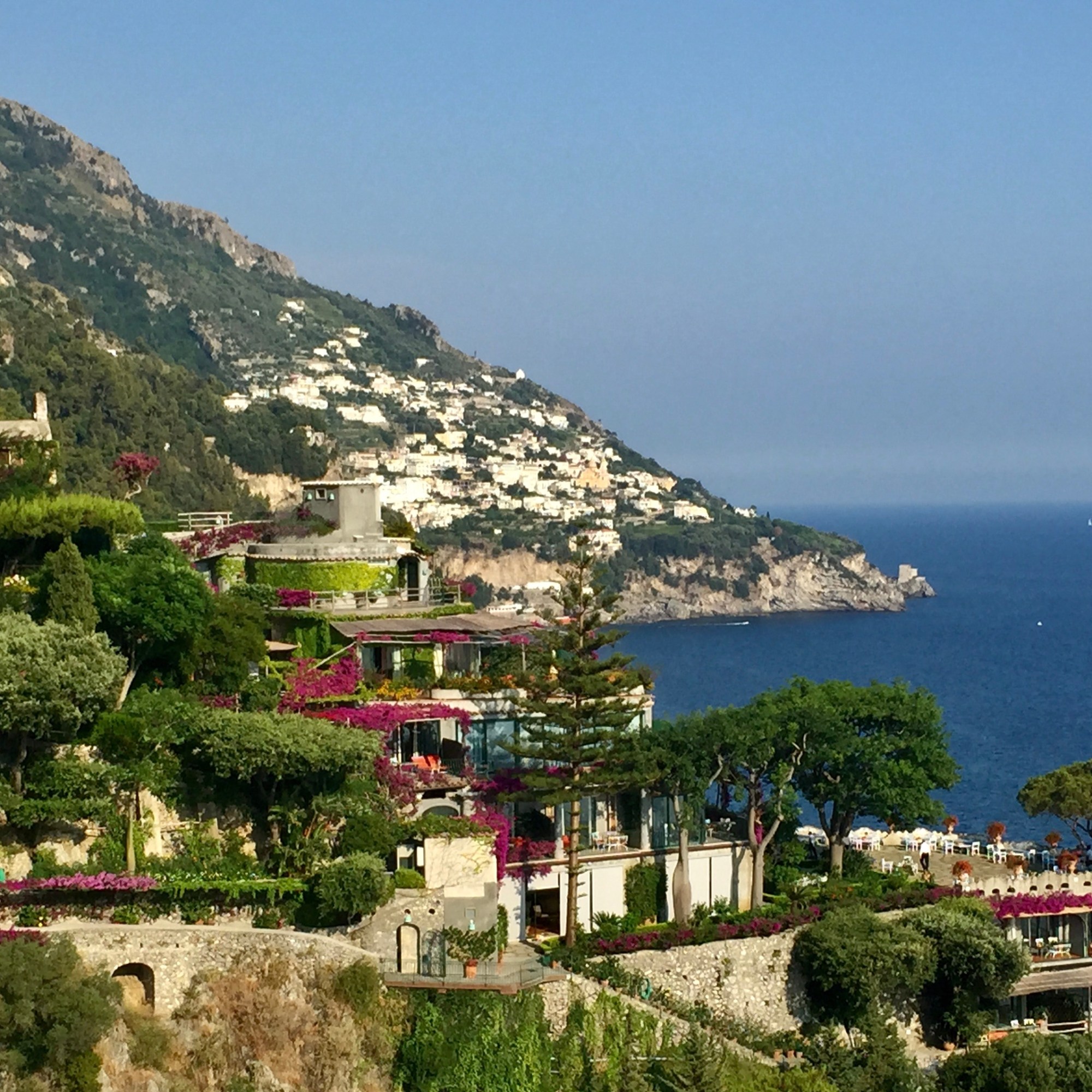 Coastal town of Italy overlooking the ocean. Lots of greenery, purple flowers, and light stone.